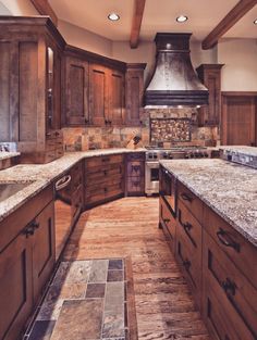 a kitchen with wooden cabinets and granite counter tops, an oven hood in the center