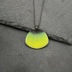 Steel, vitreous enamel in a vibrant yellow-green and oxidized sterling silver come together to create this unique necklace. Pendant is 1 inch in length and the chain is adjustable between 16 and 18 inches. Handmade in San Francisco, CA. Green Enamel Pendant Necklace, Green Oxidized Pendant Necklace, Green Jewelry With Black Enamel For Gift, Green Jewelry With Black Enamel As A Gift, Green Enamel Jewelry With Black Enamel, Modern Green Enamel Jewelry, Green Enamel Round Pendant Jewelry, Green Hand-forged Pendant Necklace, Green Enamel Necklace With Large Pendant