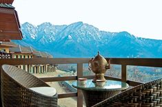 a table and chairs on a balcony with mountains in the background