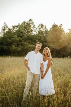 a man and woman are standing in tall grass with the sun shining on their faces