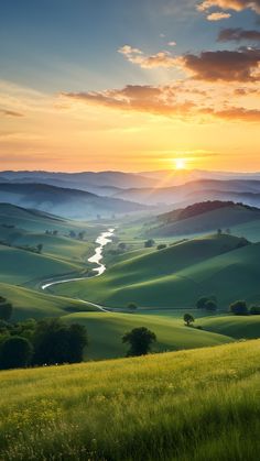 the sun is setting over rolling hills and valleys in the distance, with water running through them