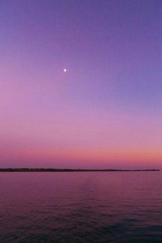 the sky is purple and pink as the sun sets in the distance over the water