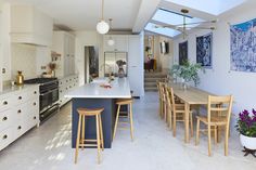 a large kitchen with an island and bar stools in the center, surrounded by white cabinets