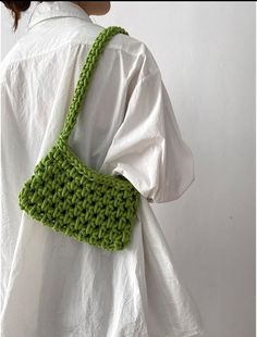 a woman wearing a white shirt holding a green crocheted purse