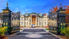 a car is parked in front of an ornate gated entrance to a large mansion