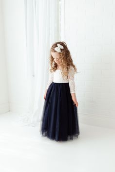 "This dress is just beautiful! It includes a delicate white lace bodice with a navy blue colored tulle skirt. The V Back with unfinished lace adds the perfect amount of boho chic look to this amazing dress. The lace sleeves are finished with the perfect amount of detail. It also includes a single flower sash that is removable. Perfect for your next special event. Nicolette's Couture is a family owned boutique based out of Dubuque, Iowa. We've had amazing success so far and believe our story is j Flower Girl Dresses Navy Blue, Navy Blue Dress Outfit, Navy Blue Flower Girl Dresses, Kids Bridesmaid Dress, Flower Girl Dresses Navy, Blue Dress Outfits, Dubuque Iowa, Lace Flower Girl Dress, Long Sleeve Ball Gowns