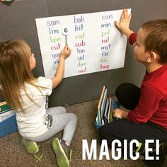 two children are sitting on the floor and playing with magnets that spell out words