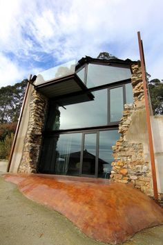 an unusual house made out of rocks and wood with glass windows on the outside wall