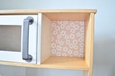 a white microwave oven sitting on top of a wooden shelf