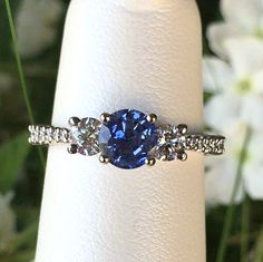 a close up of a ring with a blue stone in the middle and diamonds around it