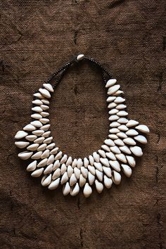 Expertly handcrafted, this African Cowrie Shell Necklace is a statement piece that adds unique and exotic flair to any outfit. Made from genuine cowrie shells, each necklace is one-of-a-kind and showcases the beauty of African craftsmanship. Elevate your style with this stunning, handmade jewelry. Length: 9" Cowrie Shell Jewelry, Cowrie Shell Necklace, Beaded Collar Necklace, Cowrie Shells, Handmade African, Beaded Collar, African Jewelry, Shell Necklace, Shell Jewelry