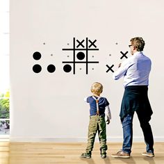 a man standing next to a little boy in front of a wall with crosses on it