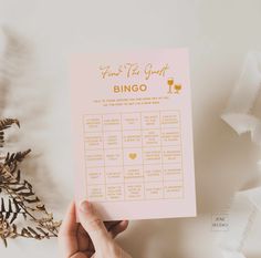 someone holding up a pink and gold wedding game