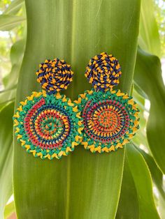 a pair of colorful earrings sitting on top of a green plant