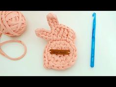 a crochet bunny is sitting next to a ball of yarn and a knitting needle