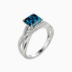 a blue diamond ring with diamonds on the sides and an intricate band around it, set in white gold