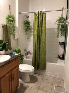 a bathroom with a shower, toilet and bathtub covered in green curtained curtains