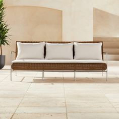 a couch sitting on top of a tiled floor next to a potted plant