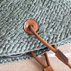 an umbrella laying on the ground next to a woven bag with leather handles and straps