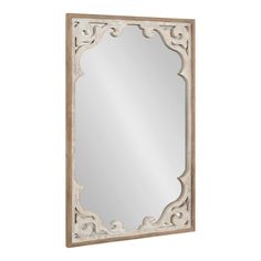 an ornate wooden framed mirror on a white wall with a light brown frame and wood trimming