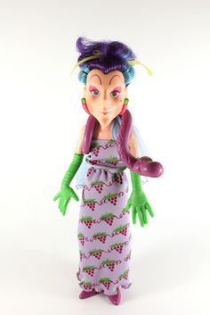 a toy doll with purple hair and green hands holding a pink object in it's right hand