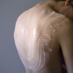 the back of a woman's shoulder with white pearls on it