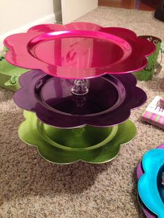 a stack of colorful plates sitting on top of a floor next to a bowl and plate holder