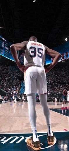 a man standing on top of a basketball court with his hands behind his back and feet in the air