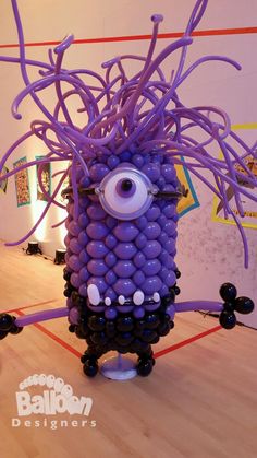 a balloon sculpture made to look like an evil minion with purple hair and eyes