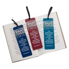 two bookmarks with the words papa pop and father printed on them are sitting next to an open book