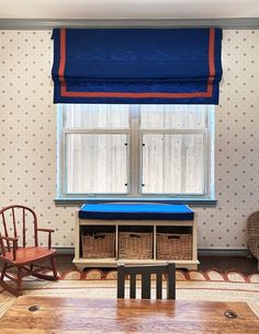 a room with two chairs and a table in front of a window that has blue fabric on it