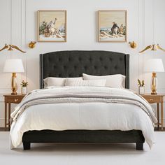 a bedroom with white walls and two lamps on either side of the bed that has a black upholstered headboard