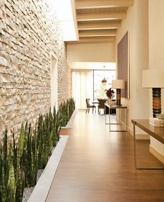 a long hallway with wood floors and brick walls, along with plants on either side