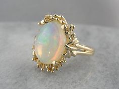 This stone has a kinetic feel, with swirling colors in the stone framed perfectly by the curving prongs and waving style of the vintage setting. The flecks inside are both pink and green, and because there is so little opacity to the stone, they shine through brilliantly. Metal: 14K Yellow Gold Gem: Opal 4.41 Carats Gem Measurements: 11.3 x 14.5 mm, Oval Ring Size: 6 Marks: "14K" Stamped on the inside band Antique Opal Ring, Chanel Costume Jewelry, Vintage Setting, Iris Fashion, Costume Jewelry Rings, Gold Fashion Necklace, Pretty Jewelry, Oval Ring, I Love Jewelry