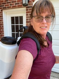 a woman wearing glasses and carrying a large white jug behind her back to the house