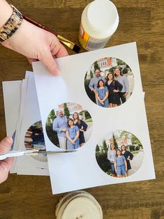 a person cutting out photos on top of paper with scissors and paintbrushes next to them