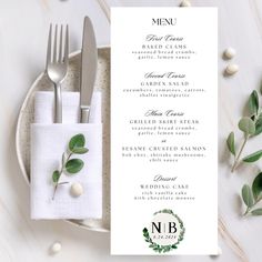 a table setting with silverware, napkins and green leaves on it in front of a menu