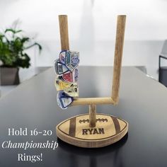 a wooden stand with rings on it sitting on top of a black table next to a potted plant