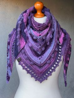 a white mannequin wearing a purple and blue crocheted shawl