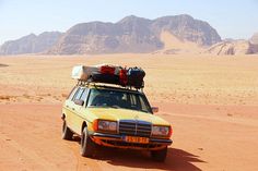 a yellow car with luggage on top in the desert