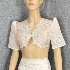 a mannequin wearing a white dress with flowers on the top and shoulderline