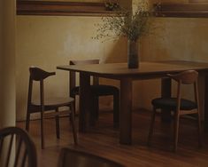 a wooden table with two chairs and a vase filled with flowers sitting on top of it