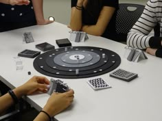 several people sitting around a table with cell phones and remotes on top of it