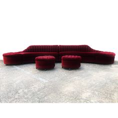 a red couch and ottoman sitting on top of a cement floor