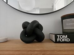 a black sculpture sitting on top of a wooden table next to a mirror and candle