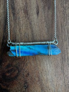 This one of a kind labradorite crystal has a stunning flash of blue and purple hues. It is a hand-polished bar of natural labradorite, wrapped with silver tone wire. The necklace chain is plated with real gold and is 16+2" in length, and the pendant measures 1" by 0.25" Each piece is unique and handmade, made by a local artist in Salt Lake City, UT. The chain is real silver plated, so it may tarnish over time. Blue Labradorite Necklaces For Healing, Blue Gemstone Necklace In Labradorite, Blue Labradorite Gemstone Necklace, Artisan Blue Labradorite Necklace, Labradorite Blue Necklace As Gift, Blue Wire Wrapped Crystal Necklace For Healing, Handmade Blue Moonstone Crystal Necklace, Spiritual Labradorite Necklaces With Raw Stone, Spiritual Labradorite Necklace With Raw Stone