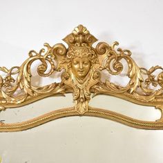 an ornate gold mirror with a woman's face on it