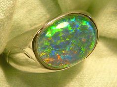 "As a rule the very best & highest quality stones are strictly reserved for our 14ct Gold range. Occasionally I set a few of the very best stones in the Sterling Silver range, this is one of those occasions. If you are prepared to pay a premium for the very best quality Opal , without the extra expense of a Solid Gold setting, this could suit. The ring is made from Sterling Silver & is fully \"J\" backed. The Gem Plus grade Triplet Opal is 14x10mm Oval & of the highest quality. The design featur Classic Oval Opal Ring With Polished Finish, Classic Oval Opal Ring Collectible, Classic Oval Hallmarked Opal Ring, Luxury Sterling Silver Oval Opal Ring, Classic Oval Rings With High Luster, Classic Oval Ring With High Luster, Modern Oval Opal Ring For Formal Occasions, Elegant Untreated Oval Gemstones, Luxury Green Oval Opal Ring