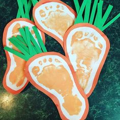 three carrots with footprints on them and green leaves