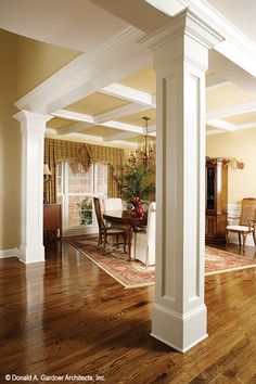 an open living room with wooden floors and white columns